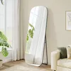 A full-length mirror stands in a well-lit room next to a sofa and a plant. Produktbild-Vorschau