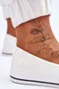 A close-up of a person's ankle wearing white sneakers and a delicate gold anklet with colorful beads. Voir les images du produit
