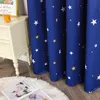 A close-up of blue curtains with white and yellow stars, draped next to a white nightstand with a glass of orange liquid and a framed picture. Produktbild-Vorschau