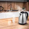 A stainless steel electric kettle is steaming next to a cup of coffee on a wooden countertop in a kitchen. Anteprima dell’immagine prodotto