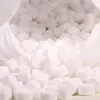 A close-up view of a pile of white salt tablets spilling out of a white bag. Produktbild-Vorschau