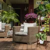 A cozy outdoor patio setting with wicker furniture and plants. Produktbild-Vorschau