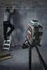 A man is using a laser level on a wall while a laser level device is in the foreground. Produktbild-Vorschau