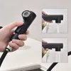 A hand holding a black kitchen faucet sprayer, with inset images showing water flow. Produktbild-Vorschau