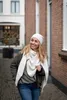 A woman walking down a cobblestone street, wearing a scarf and beanie. Produktbild-Vorschau