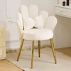A white velvet armchair with gold legs sits on a rug in a room with a dresser and a vanity in the background. Podgląd zdjęcia produktu