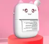 A cute, cat-themed mini printer is displayed on a pink and red pedestal against a pink background. Produktbild-Vorschau