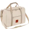 A beige duffel bag with brown accents and a logo, shown against a white background. Náhled obrázku produktu