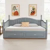 A grey daybed with two drawers underneath, set against a white wall with two abstract art pieces hanging above it. The daybed is made up with a light grey mattress and a patterned cushion. Náhled obrázku produktu