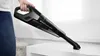 A person is holding a black handheld vacuum cleaner over a white surface. Podgląd zdjęcia produktu