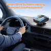 A person's hands are on the steering wheel of a car, with a small device placed on the dashboard. Produktbild-Vorschau