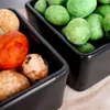 A close-up view of two black ceramic bowls filled with various types of seasoned peanuts. Voir les images du produit