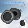 Two black ear pads for headphones are shown against a light blue and white background with a faint outline of an ear. Produktbild-Vorschau