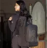 A woman is carrying a black bag with a logo on it, possibly in a stable or barn setting. Produktbild-Vorschau
