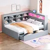 A gray corner bed with built-in shelving and LED lighting, set in a child's bedroom with a pink cloud mural and a space-themed rug. Produktbild-Vorschau