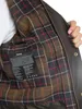 Close-up of the inside lining of a jacket, showing a plaid pattern and a care label. Produktbild-Vorschau