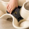 A hand is shown placing a black insert into a cream-colored tiered planter. Voir les images du produit