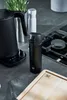 A kitchen counter with a black kettle, a black thermos, a white dispenser, and a wooden cutting board. Podgląd zdjęcia produktu