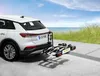 A white car with a bike rack attached is parked on a paved surface near a body of water and grassy area. Produktbild-Vorschau