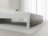 A low-angle shot of a white bed frame with a wood-grain headboard, set against a white wall and curtains. Náhled obrázku produktu