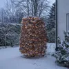 A bush decorated with warm white LED lights in a snowy garden. Podgląd zdjęcia produktu
