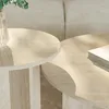 A close-up view of two round travertine coffee tables, one slightly overlapping the other, with a book on the larger table. Produktbild-Vorschau