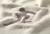 A close-up of a textured blanket with a dark brown graphic of a skier. Produktbild-Vorschau