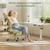 A woman relaxing in a green ergonomic office chair at a white desk in a bright room with a large window. Podgląd zdjęcia produktu