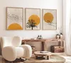 A living room scene featuring three framed artworks on a wall above a wooden console table, with a plush armchair in the foreground. Anteprima dell’immagine prodotto