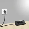 A black power strip with multiple outlets and USB ports sits on a wooden surface, connected to a wall outlet by a black cable. Produktbild-Vorschau