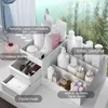 A white makeup organizer filled with various cosmetic products, placed on a white surface, with a blurred natural background of trees and sky. Náhľad obrázku produktu