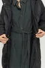 A close-up shot of a woman wearing a black puffer coat and a dark green corduroy dress. Produktbild-Vorschau