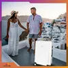 A couple holding hands on a balcony with a view of a white village and blue domes. Produktbild-Vorschau