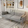 A gray sofa with a diamond pattern on the backrest is placed on a patterned rug in a living room setting. A framed picture hangs on the wall behind the sofa, and a lamp is visible to the right. Voir les images du produit