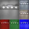 A collage of images showing a white LED ceiling light with four adjustable spotlights. The light is shown in different colored environments: white, blue-gray, beige, red, green, and blue. Produktbild-Vorschau