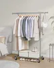 A clothing rack with clothes and shoes in a bedroom setting. Produktbild-Vorschau