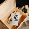 An open wooden box filled with photos, envelopes, and a book, with a bouquet of flowers in the background. Náhled obrázku produktu