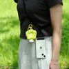 A person wearing a dark shirt and striped pants, with a phone and a flower-shaped charm attached to a lanyard around their neck. Produktbild-Vorschau