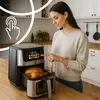 A woman is using a digital display on an air fryer in a kitchen setting. Produktbild-Vorschau