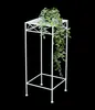 A white metal plant stand with a trailing green plant on top, set against a black background. Anteprima dell’immagine prodotto