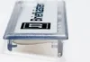 A close-up, angled view of a name tag with text and a logo. Produktbild-Vorschau