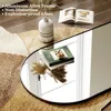 A close-up of a large oval mirror reflecting books and a vase, placed on a rug. Anteprima dell’immagine prodotto