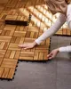 A woman is laying down wooden tiles on a gray floor. Náhled obrázku produktu