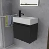 A modern bathroom vanity with a black cabinet and white sink, mounted on a gray tiled wall. Towels hang on a rack to the left. Produktbild-Vorschau