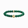 A bracelet with green beads and a gold centerpiece, displayed on a white background. Produktbild-Vorschau