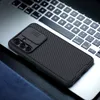A black phone case with a sliding camera cover is placed on a laptop keyboard. Voir les images du produit