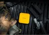Tactical gear including a power bank, gun magazines, a flashlight, and gloves are laid out on a textured black surface. Produktbild-Vorschau