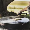 A person is pouring oil onto food being cooked on a large outdoor grill. Anteprima dell’immagine prodotto
