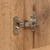A close-up shot of a cabinet hinge attached to a wooden surface. Náhled obrázku produktu