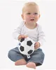 A baby sitting on the floor holding a soft toy soccer ball. Produktbild-Vorschau